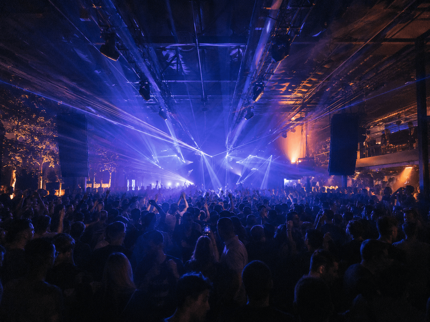 A packed Noctessa dancefloor lit by a warm beam through haze
